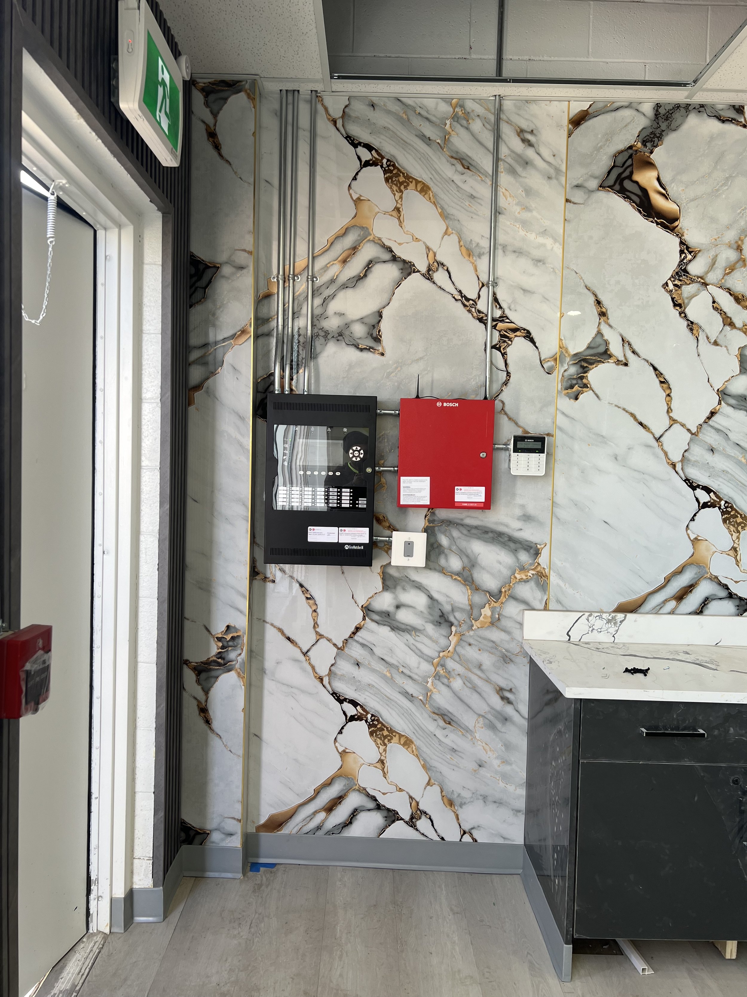 Commercial fire alarm panel installed on a marble feature wall